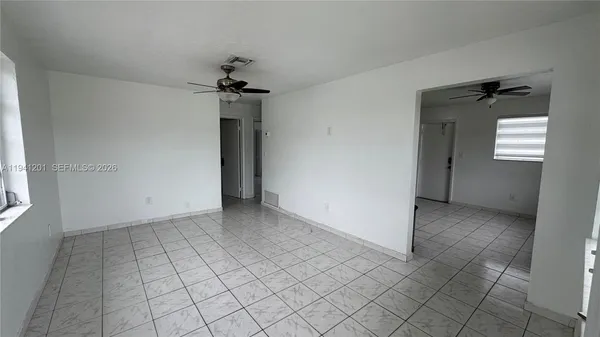an empty room with windows and fan
