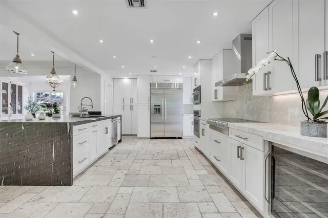 a kitchen with stainless steel appliances granite countertop a stove a refrigerator a sink a stove a dining table and chairs