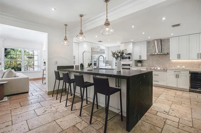 a kitchen with stainless steel appliances kitchen island granite countertop a sink a stove a dining table and chairs