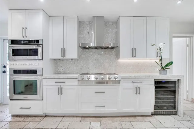 a kitchen with stainless steel appliances kitchen island granite countertop a table chairs and a refrigerator