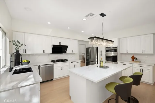 a large white kitchen with a large window and stainless steel appliances