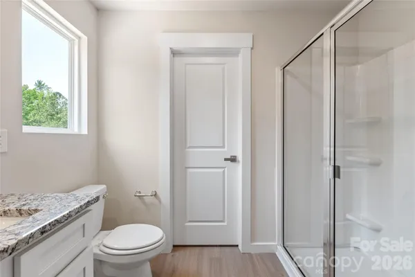 a bathroom with a granite countertop toilet a sink and a window