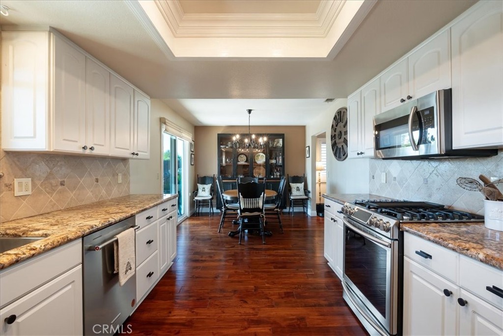 1321 June Street Fallbrook, CA 92028 - Photo 15 of 44 a kitchen with stainless steel appliances granite countertop a stove top oven a sink dishwasher and white cabinets with wooden floor