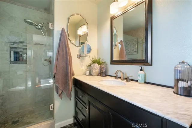 a bathroom with a granite countertop sink a mirror and shower