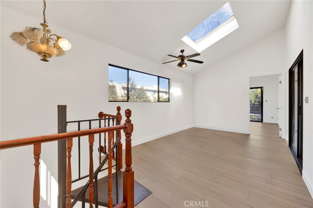 20243 Lanark Street Winnetka, CA 91306 - Photo 29 of 38 a view of a hallway with a chandelier fan and wooden floor