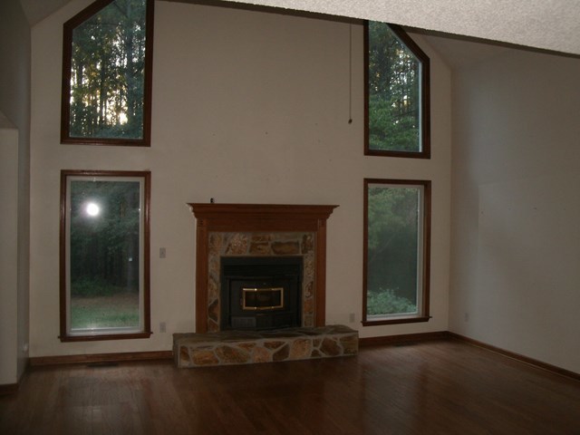 199 Cyler Road Gray, GA 31032 - Photo 3 of 23 an empty room with wooden floor a fireplace and entryway