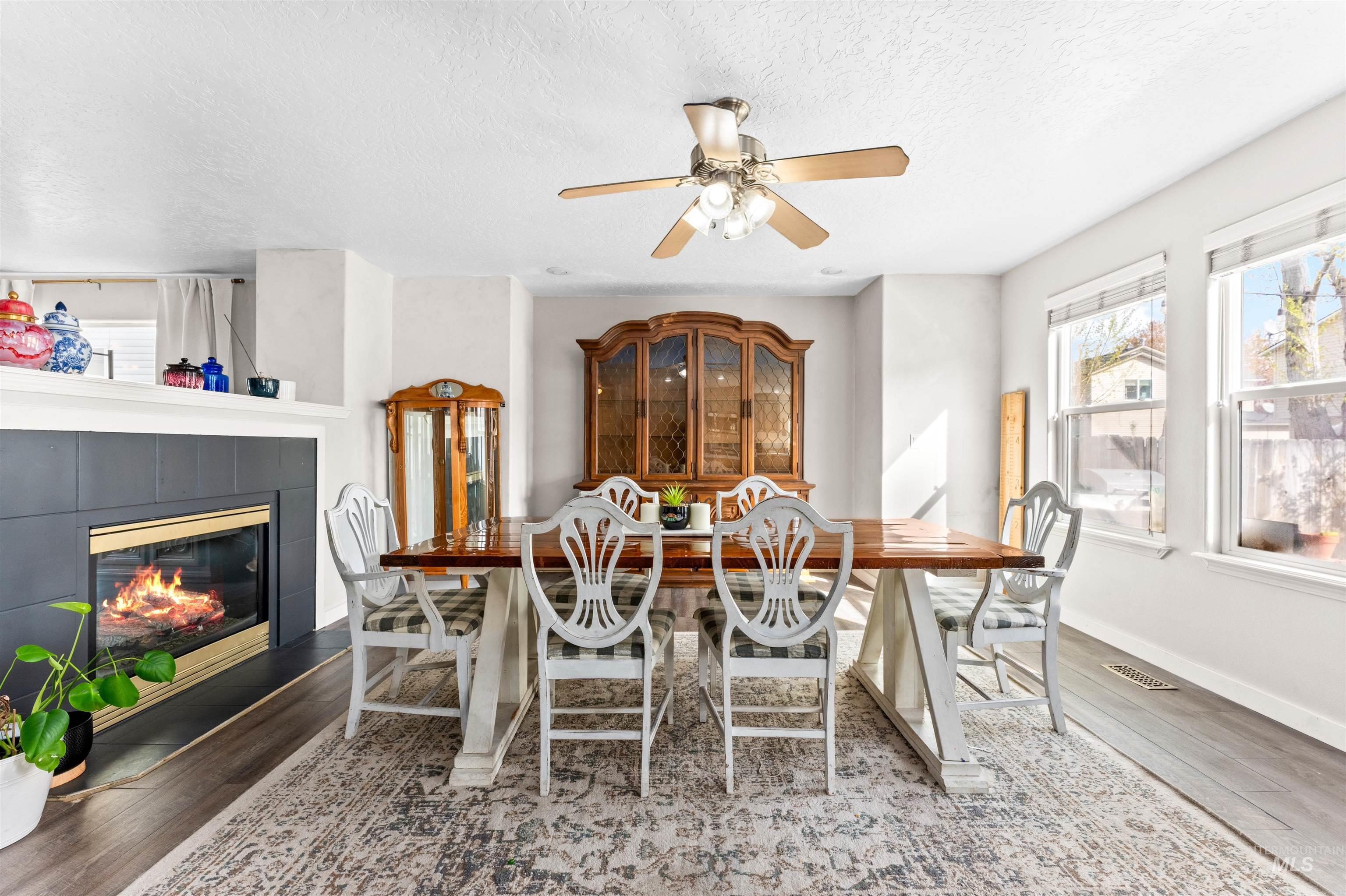 5021 Lathrop Place Caldwell, ID 83607 - Photo 11 of 43 Dining area featuring wood finished floors, plenty of natural light, a ceiling fan, a fireplace, and a textured ceiling
