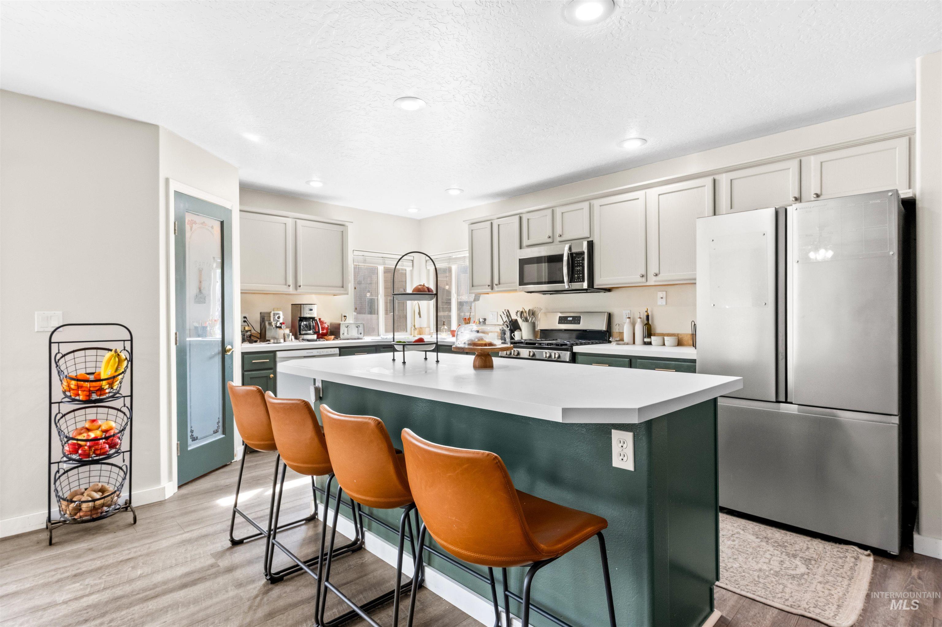 5021 Lathrop Place Caldwell, ID 83607 - Photo 14 of 43 Kitchen featuring stainless steel appliances, light countertops, light wood finished floors, a center island, and green cabinets