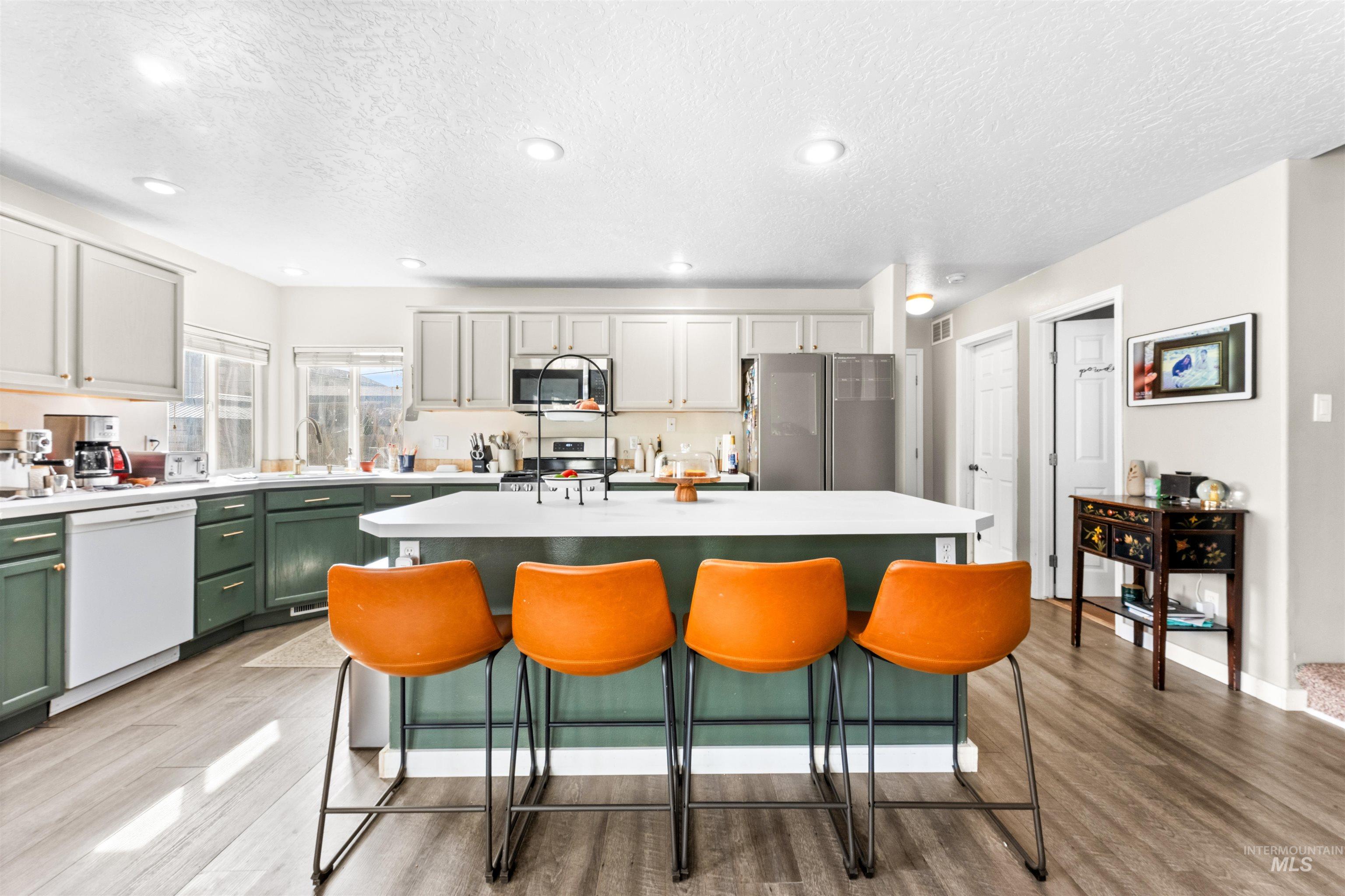 5021 Lathrop Place Caldwell, ID 83607 - Photo 15 of 43 Dual tone kitchen with a center island, stainless steel appliances, light wood-type flooring, a textured ceiling, and a breakfast bar