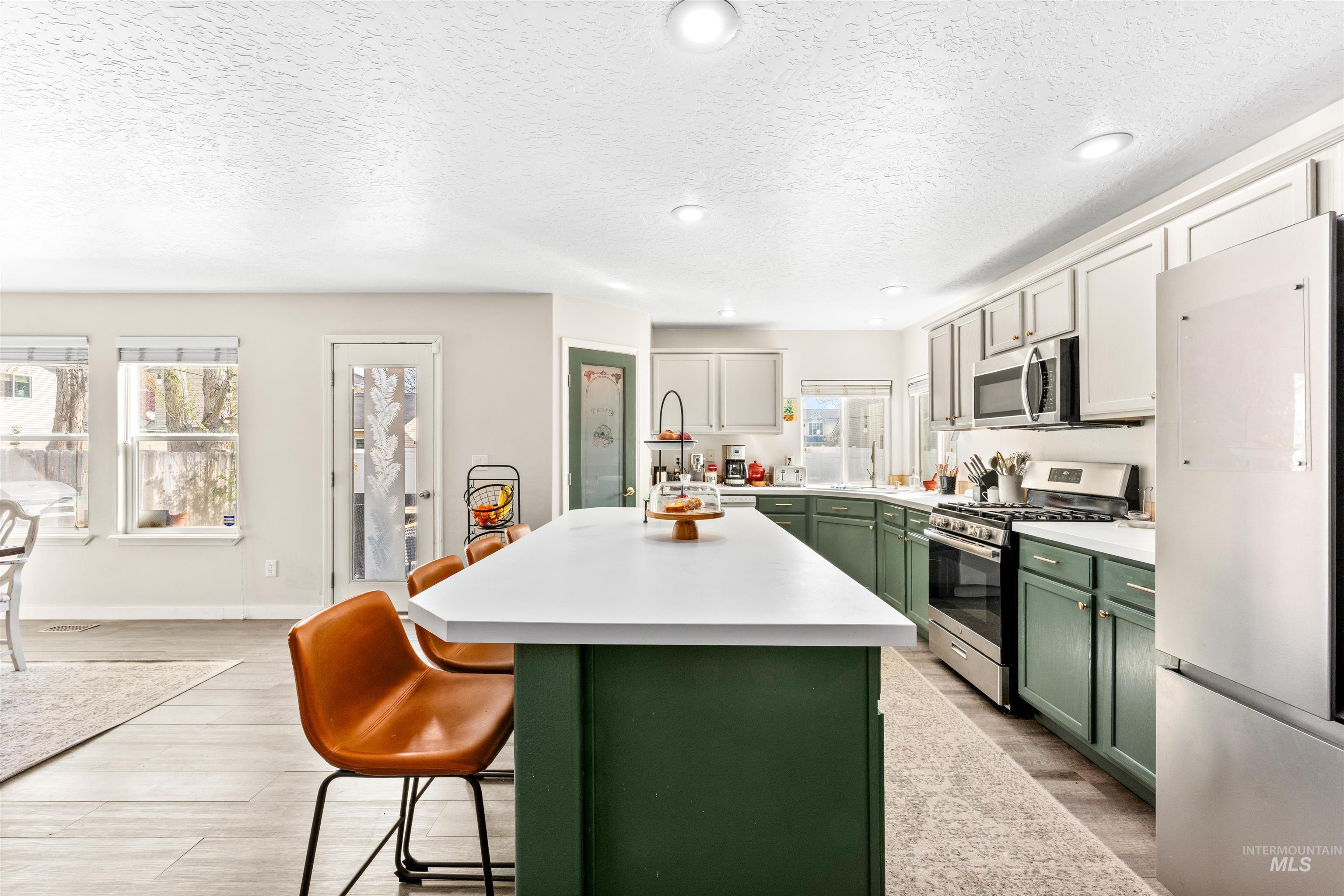 5021 Lathrop Place Caldwell, ID 83607 - Photo 16 of 43 Dual tone kitchen featuring stainless steel appliances, light countertops, light wood-style floors, a breakfast bar, and a center island