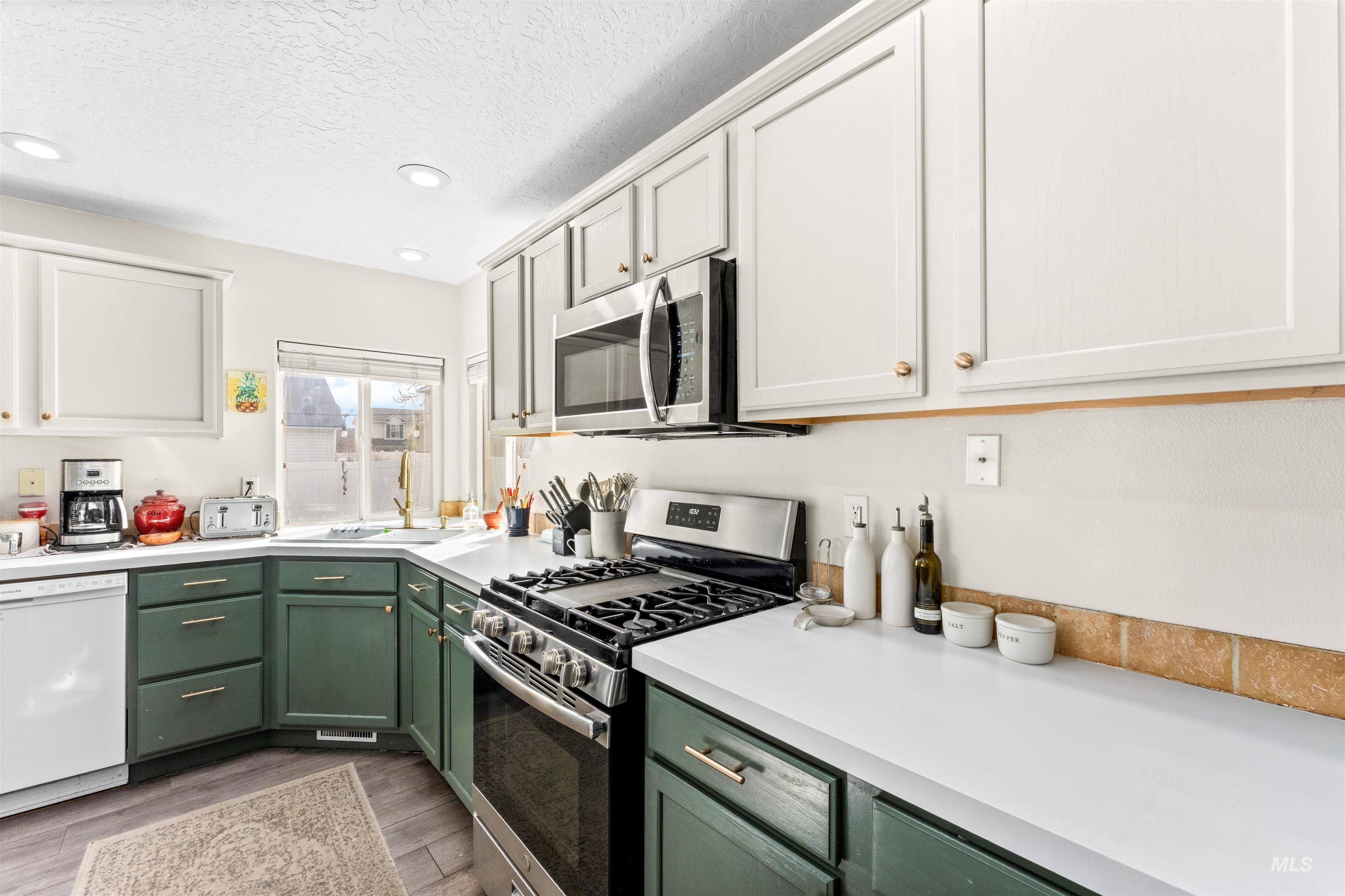 5021 Lathrop Place Caldwell, ID 83607 - Photo 17 of 43 Kitchen featuring stainless steel appliances, light countertops, two tone cabinets, a textured ceiling, and dark wood finished floors
