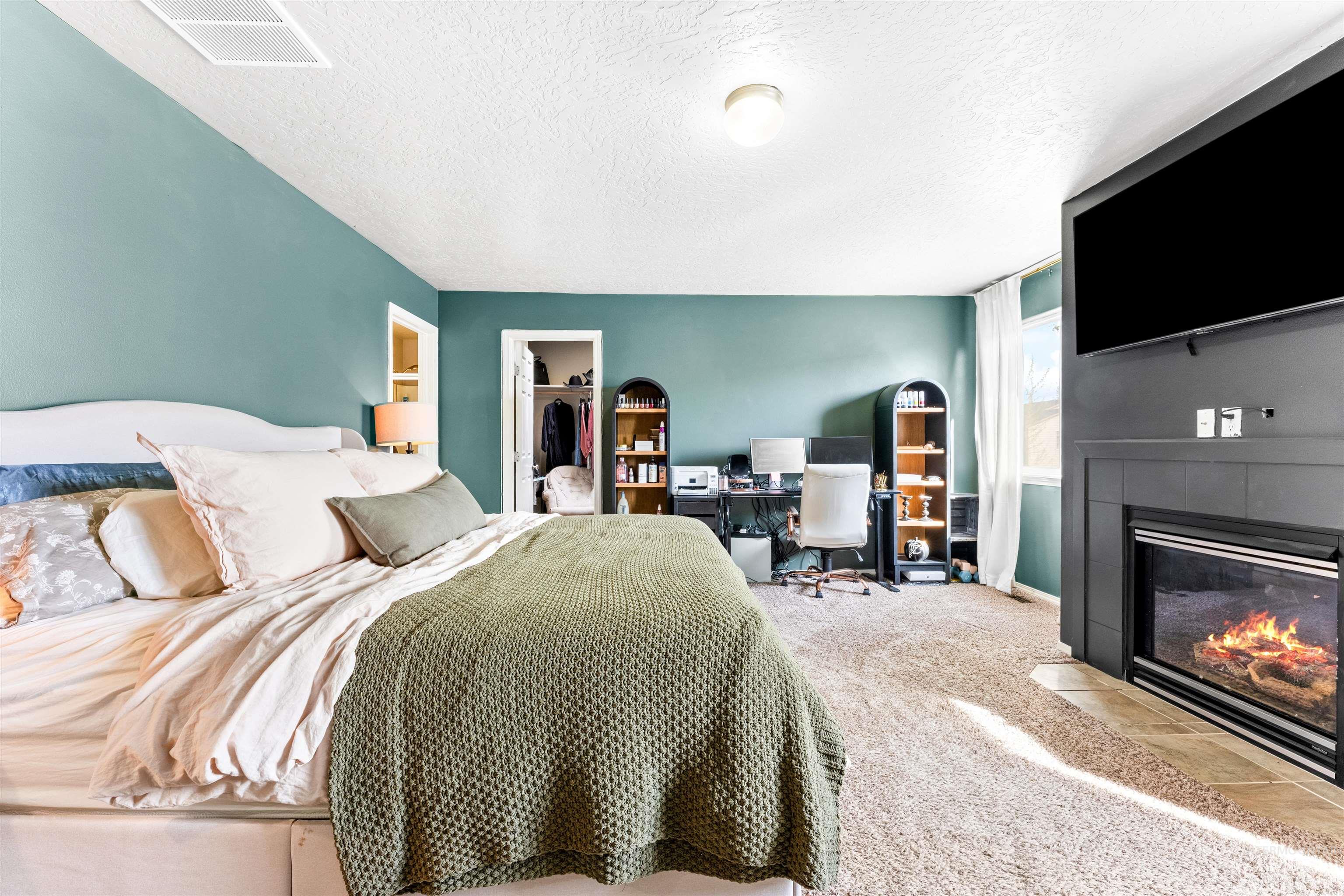 5021 Lathrop Place Caldwell, ID 83607 - Photo 22 of 43 Bedroom featuring a walk in closet, a desk, a tiled fireplace, carpet floors, and a textured ceiling