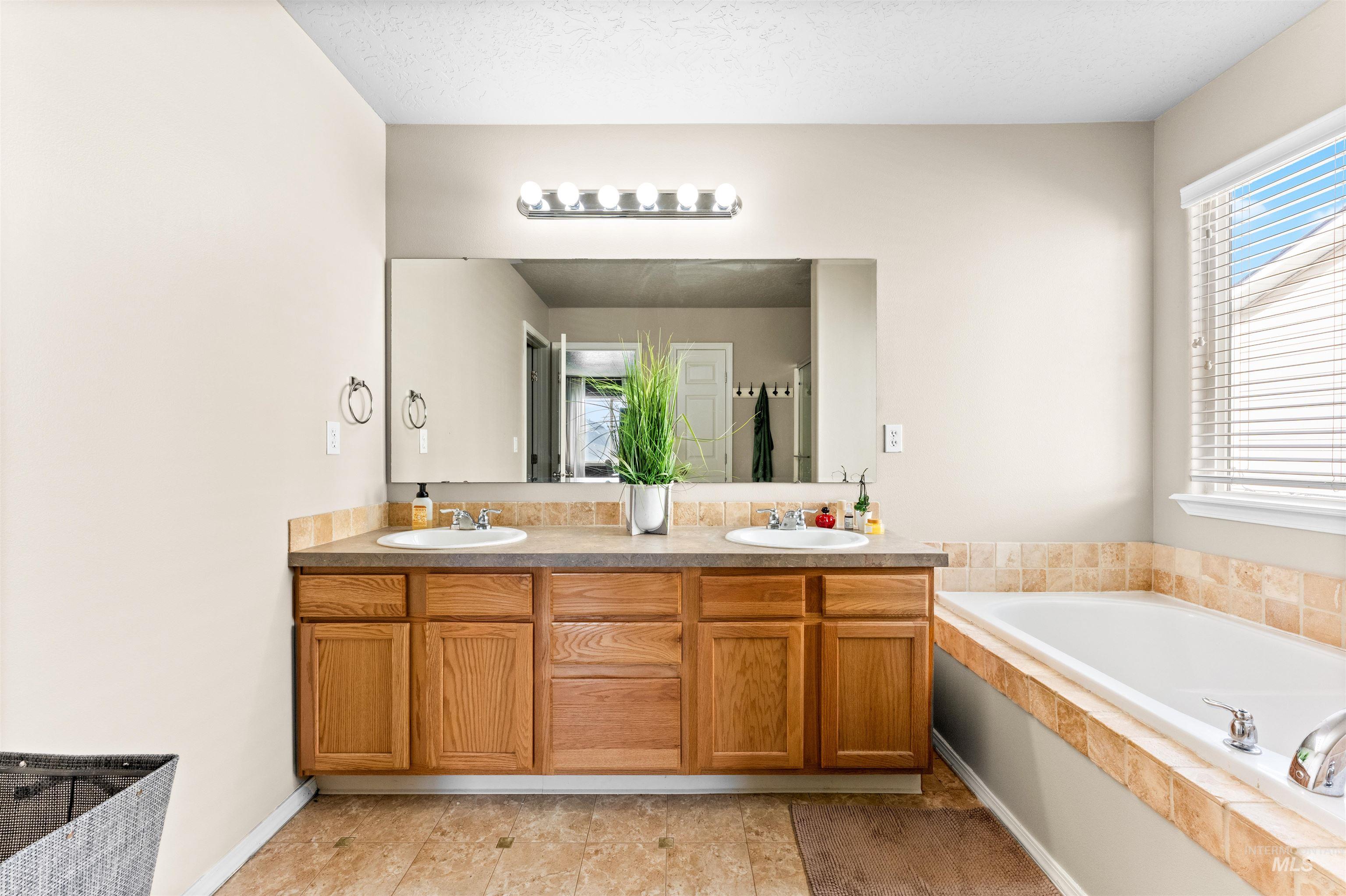 5021 Lathrop Place Caldwell, ID 83607 - Photo 25 of 43 Full bathroom featuring a garden tub, double vanity, plenty of natural light, and a textured ceiling
