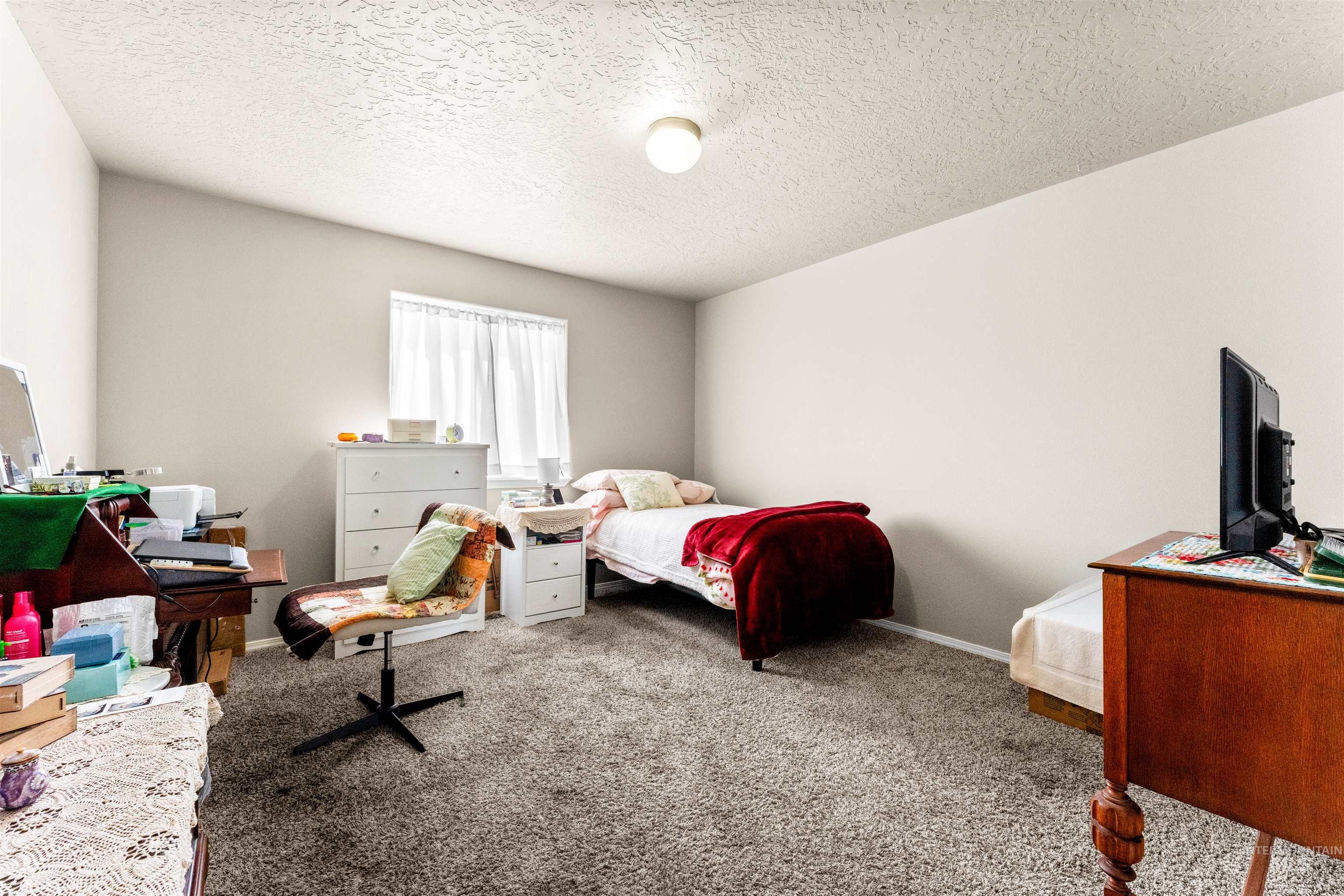 5021 Lathrop Place Caldwell, ID 83607 - Photo 26 of 43 Carpeted bedroom featuring a textured ceiling and baseboards
