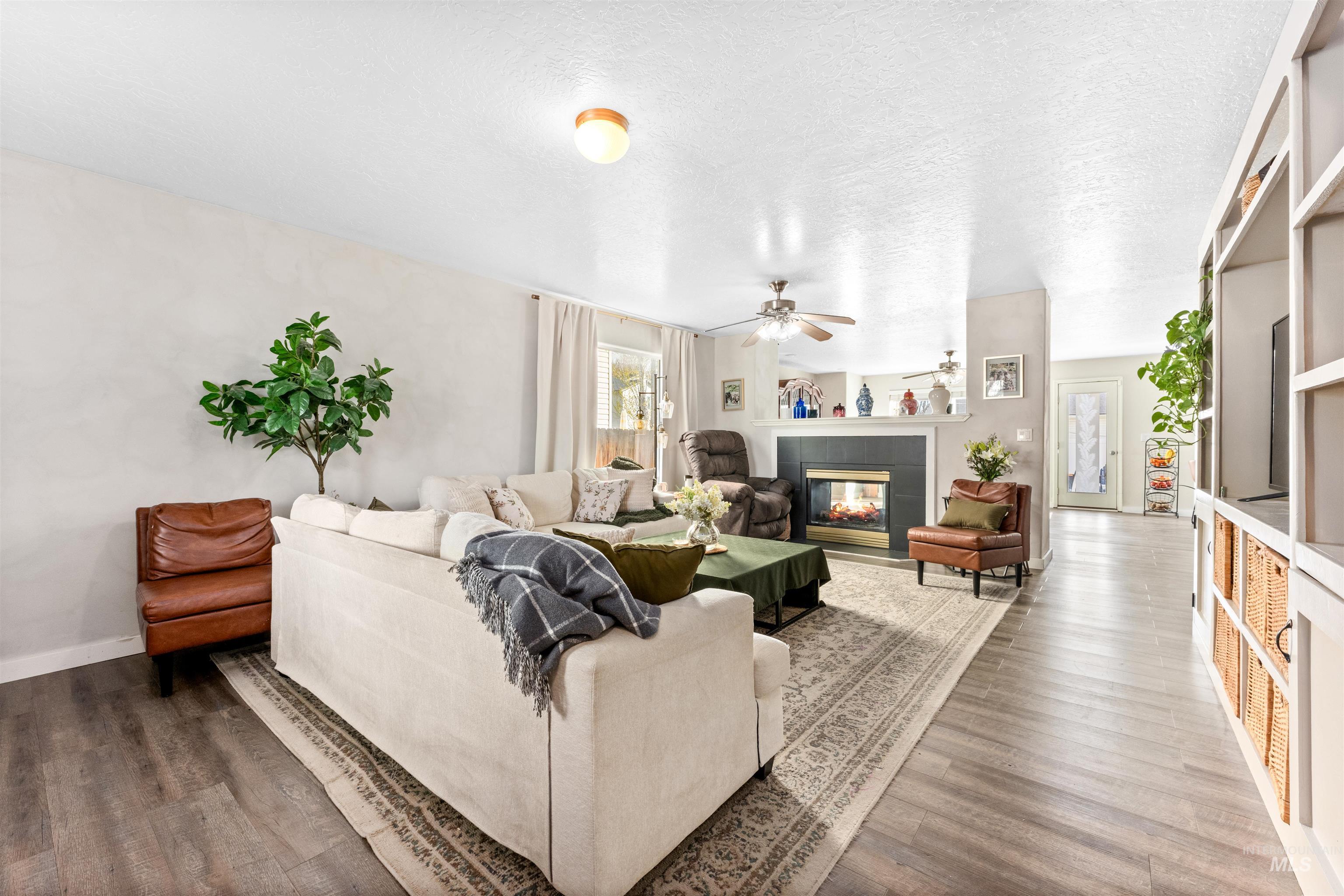 5021 Lathrop Place Caldwell, ID 83607 - Photo 6 of 43 Living room with a fireplace, a textured ceiling, wood finished floors, and a ceiling fan