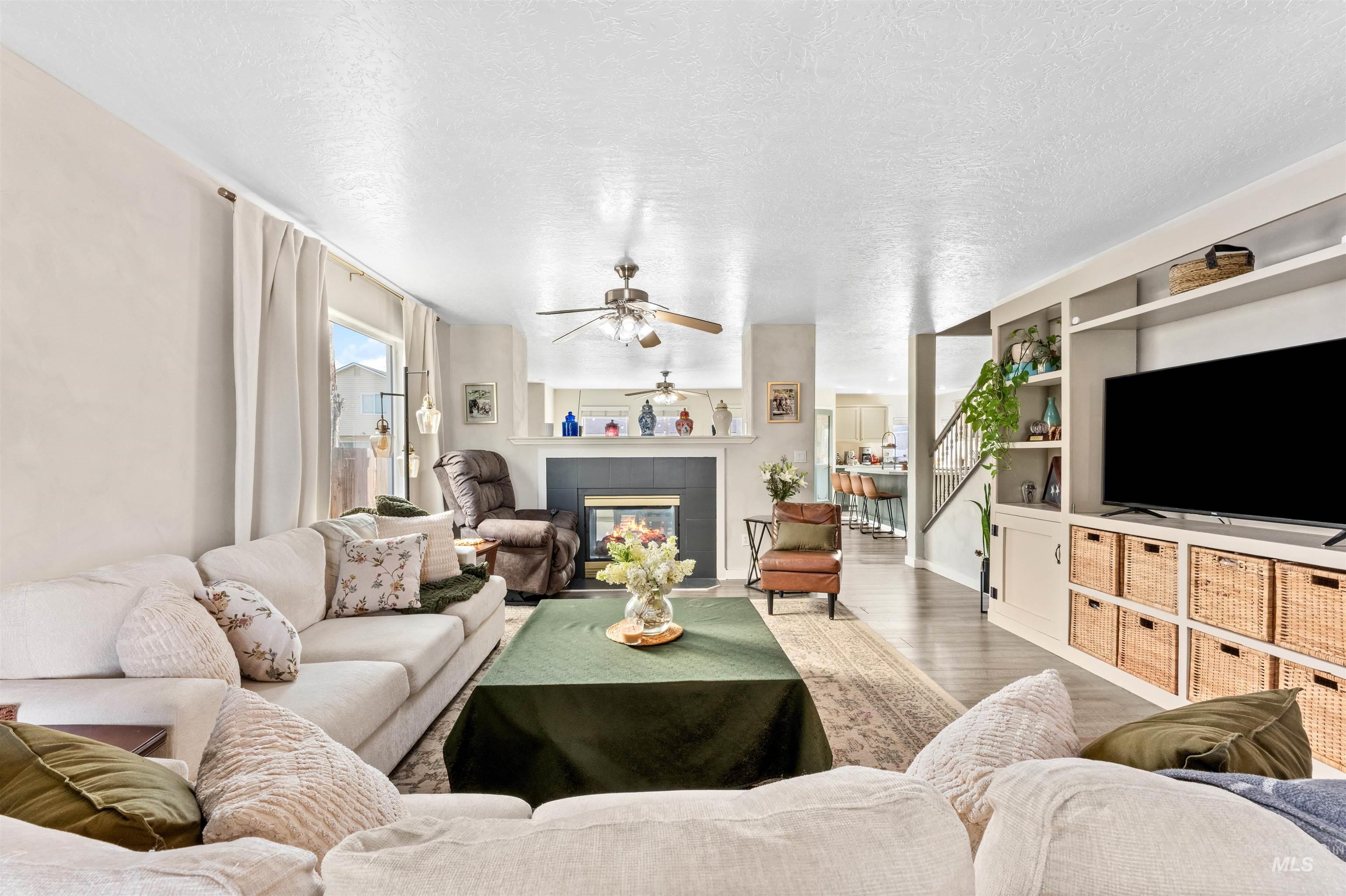 5021 Lathrop Place Caldwell, ID 83607 - Photo 7 of 43 Living area featuring wood finished floors, a tile fireplace, a textured ceiling, and a ceiling fan