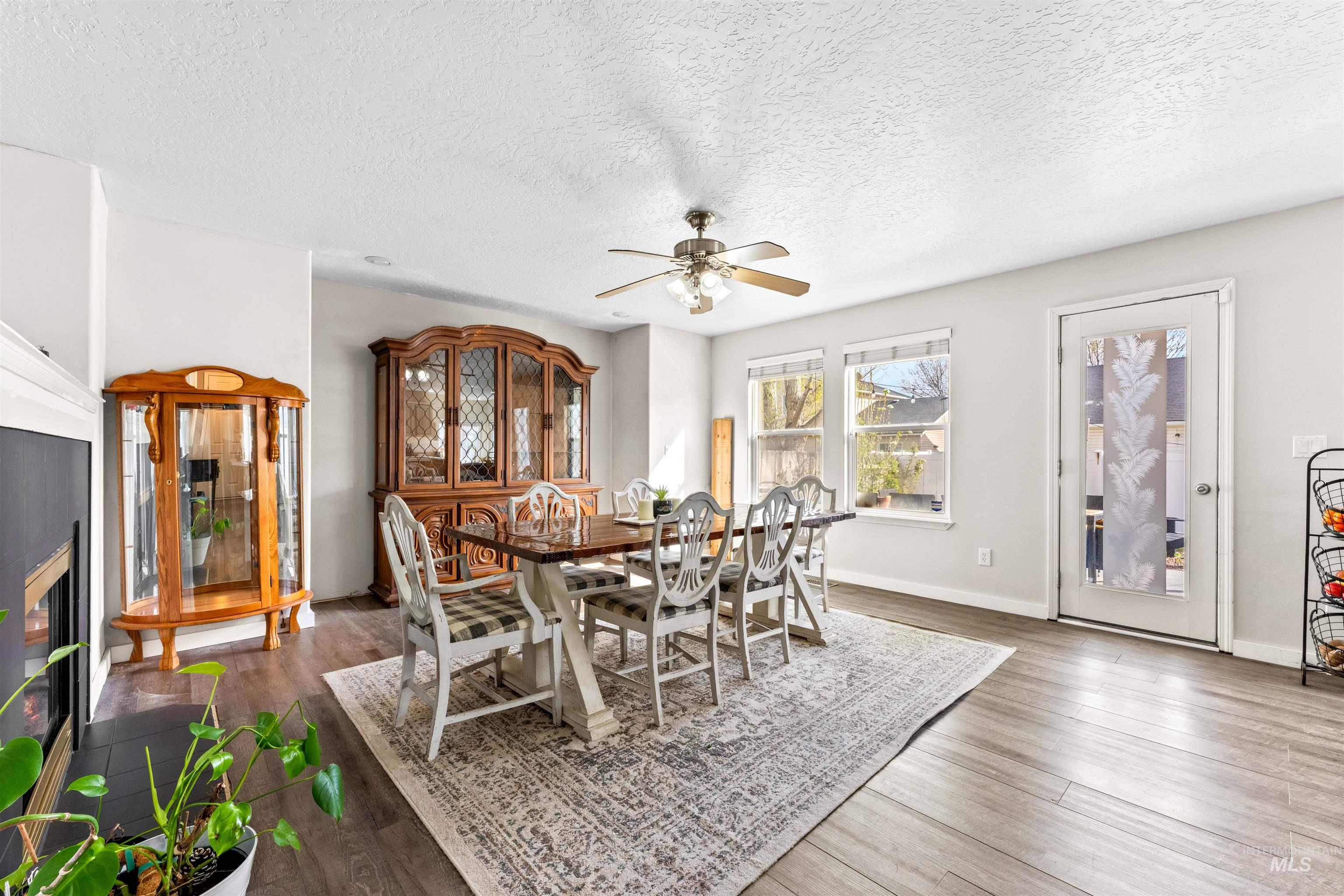 5021 Lathrop Place Caldwell, ID 83607 - Photo 10 of 43 Dining space with a glass covered fireplace, wood finished floors, ceiling fan, and a textured ceiling