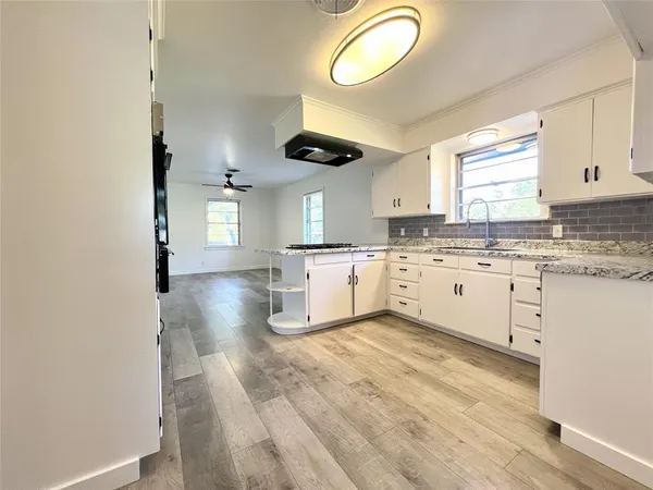 a kitchen with granite countertop a sink cabinets stainless steel appliances and a window