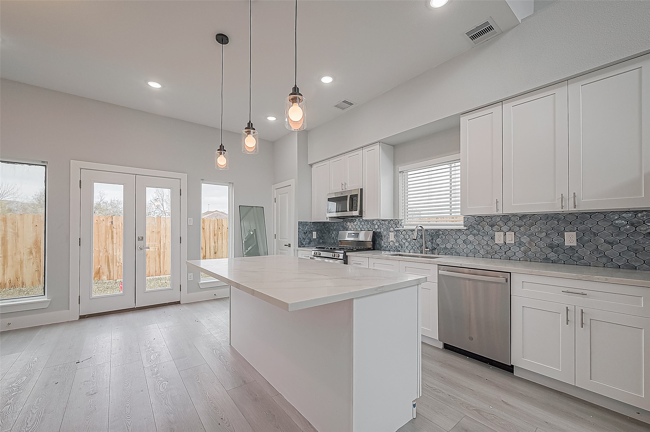 9204 Buffum Street Houston, TX 77051 - Photo 6 of 19 a large white kitchen with kitchen island a sink dishwasher a stove and white countertops with wooden floor