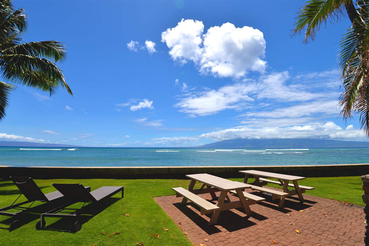 4435 Lower Honoapiilani Road, Unit 115 Lahaina, HI 96761 - Photo 11 of 26 a view of a backyard with lawn chairs under an umbrella