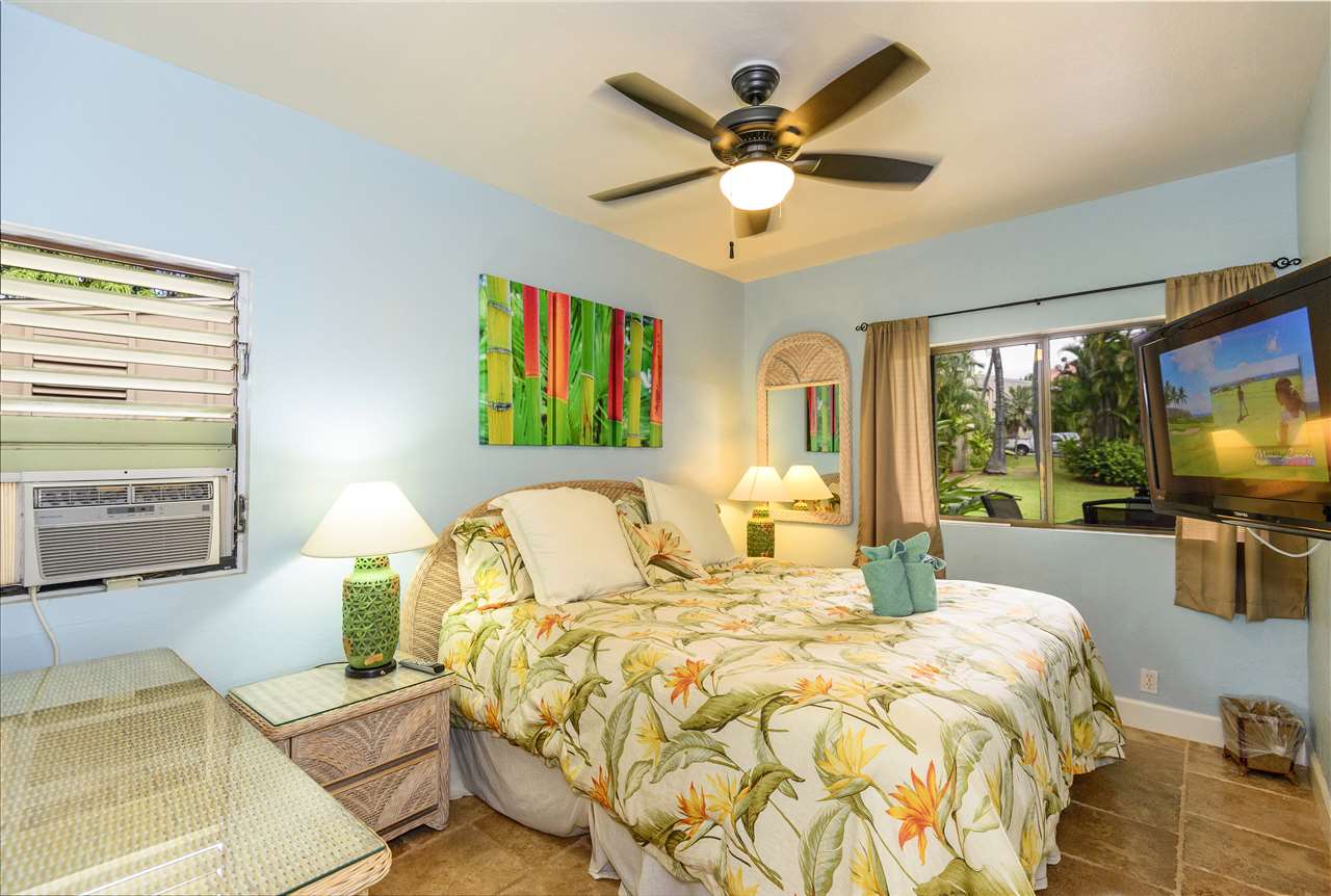4435 Lower Honoapiilani Road, Unit 115 Lahaina, HI 96761 - Photo 14 of 26 a bedroom with a bed a chandelier and a flat tv screen on dresser