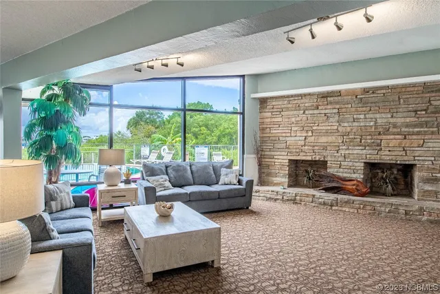 a living room with furniture a rug kitchen view and large windows