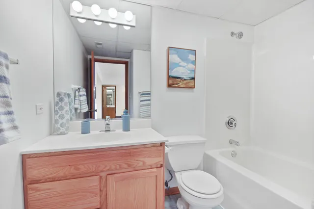 a bathroom with a granite countertop sink a toilet a mirror and bathtub