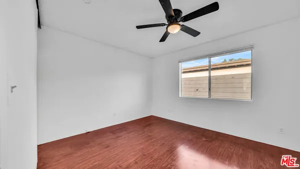 a view of empty room with wooden floor and fan