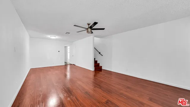 a view of empty room with wooden floor and ceiling fan