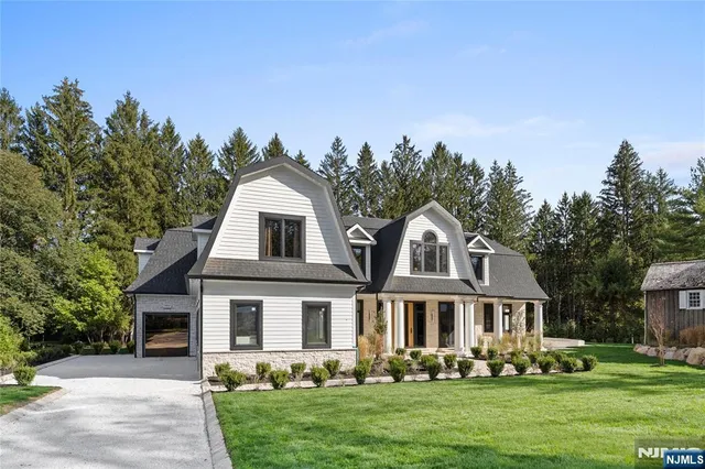 a front view of a house with a garden and trees