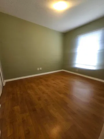 an empty room with wooden floor and windows in it