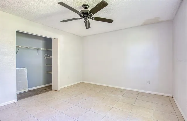 an empty room with a ceiling fan and carpet