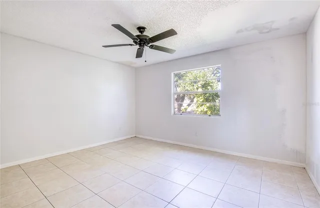an empty room with windows and fan