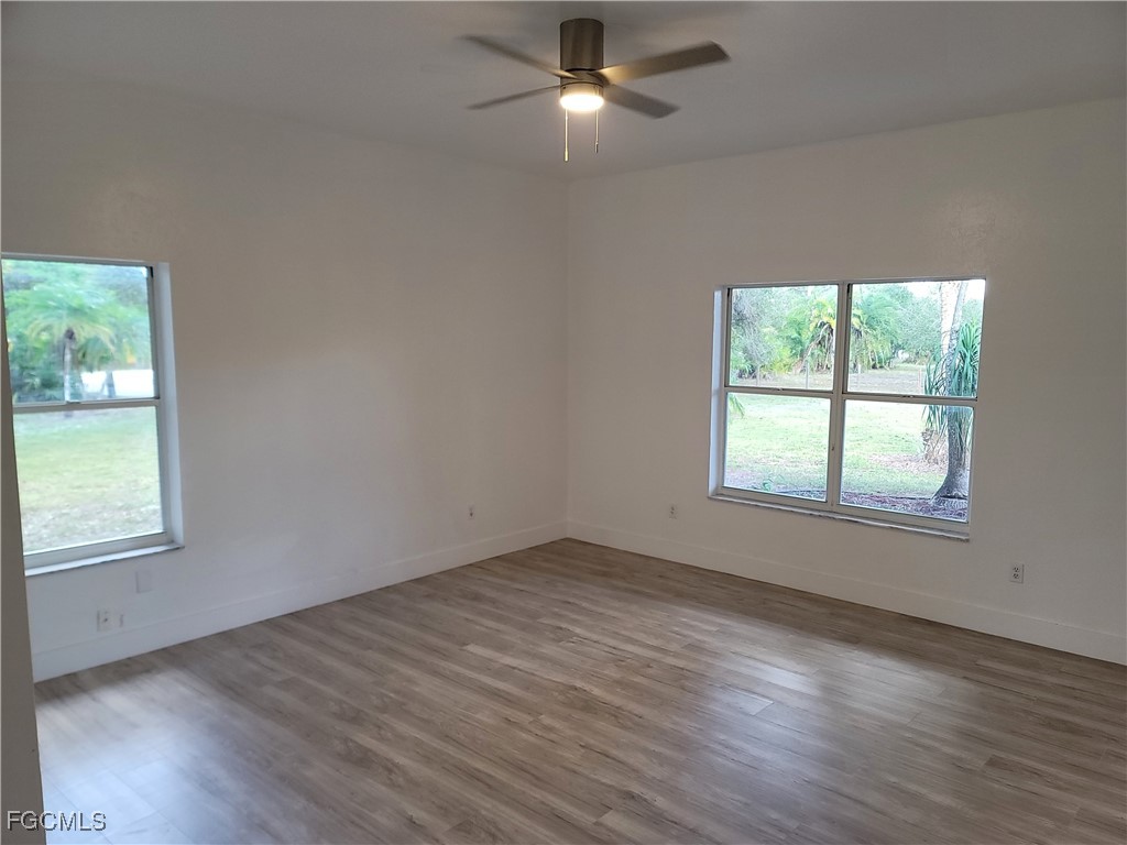 7820 Rich Road North Fort Myers, FL 33917 - Photo 14 of 26 an empty room with wooden floor chandelier fan and windows