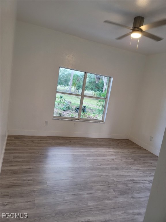 7820 Rich Road North Fort Myers, FL 33917 - Photo 17 of 26 an empty room with wooden floor chandelier fan and windows