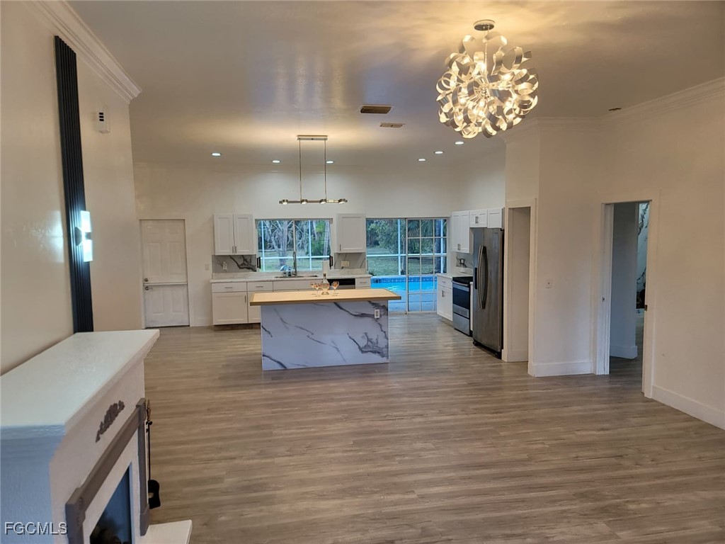 7820 Rich Road North Fort Myers, FL 33917 - Photo 23 of 26 a large kitchen with stainless steel appliances granite countertop a large counter top a stove a refrigerator and a chandelier