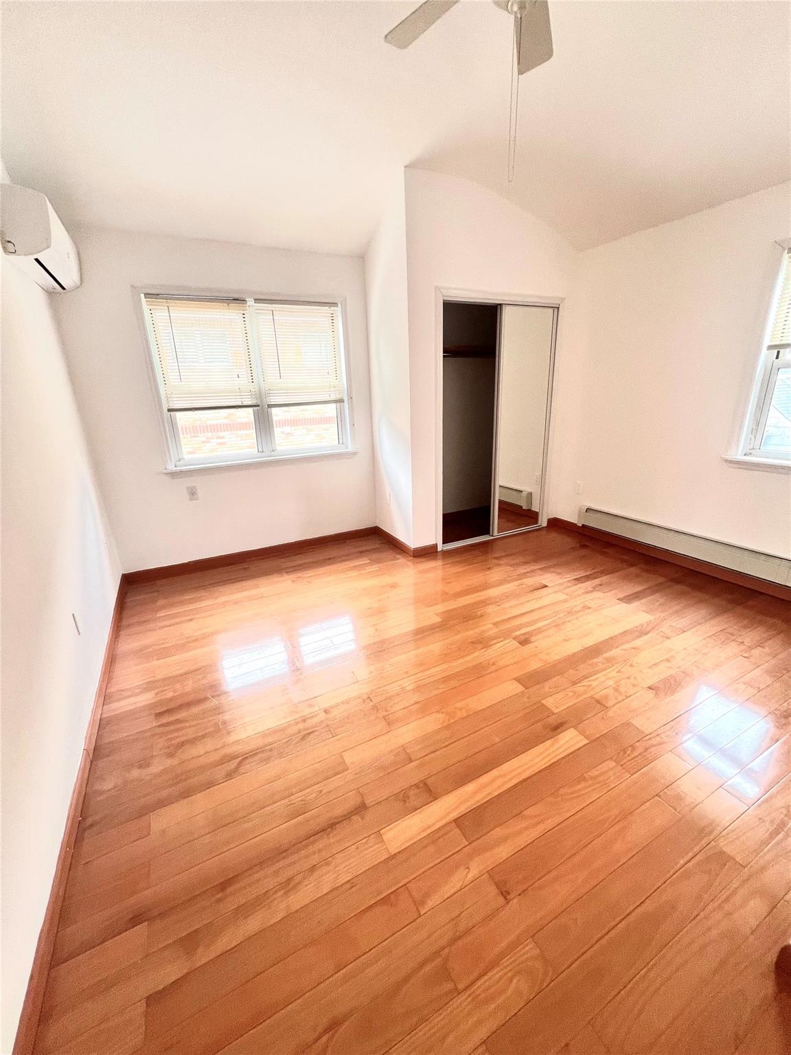 200-29 45th Road, Unit 2 Queens, NY 11361 - Photo 12 of 14 an empty room with wooden floor cabinet and windows