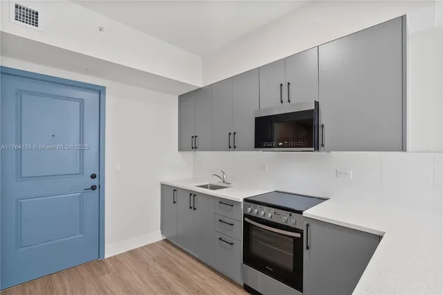 a kitchen with stainless steel appliances a stove microwave and sink