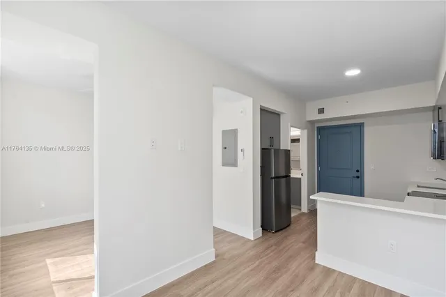 a view of a refrigerator in kitchen and an empty room