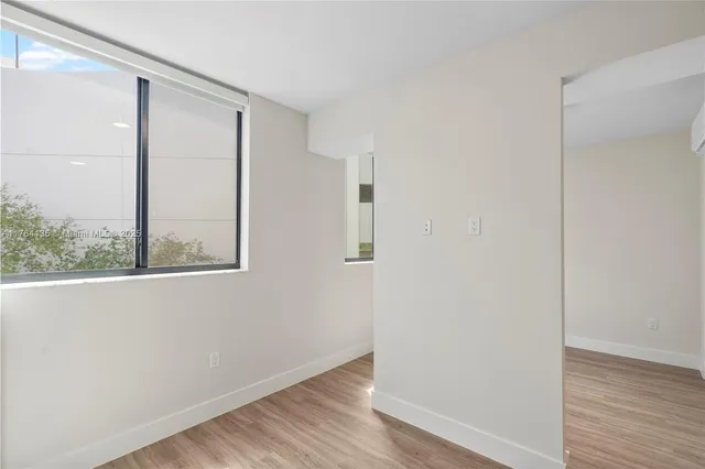 an empty room with wooden floor and a window