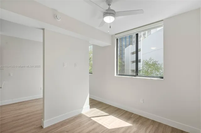 a view of an empty room with wooden floor and a window