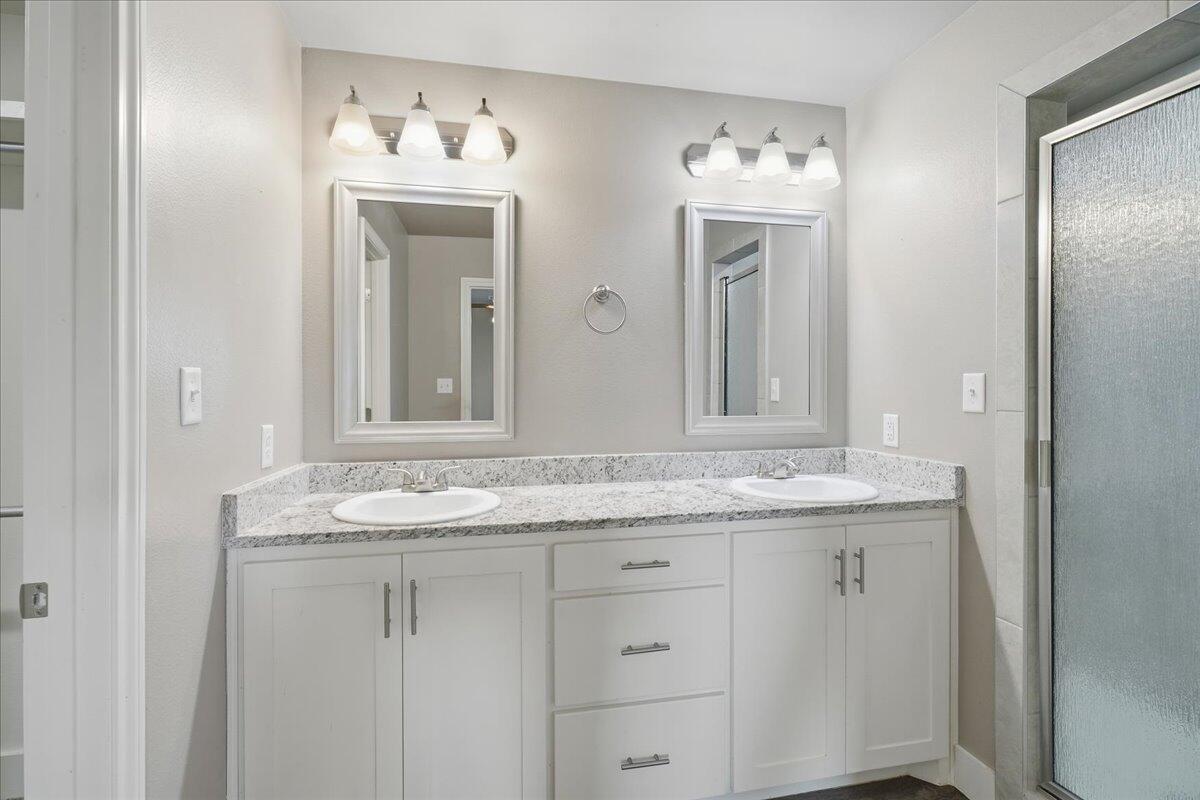 7502 89th Street Lubbock, TX 79424 - Photo 12 of 26 a bathroom with a granite countertop sink and a mirror