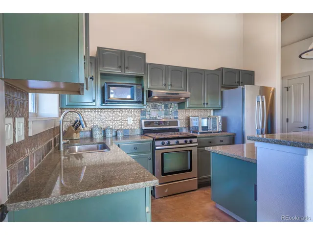 a kitchen with stainless steel appliances granite countertop a stove a sink and a microwave