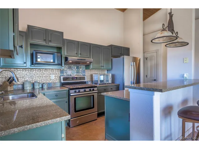 a kitchen with stainless steel appliances granite countertop a stove a sink and a microwave