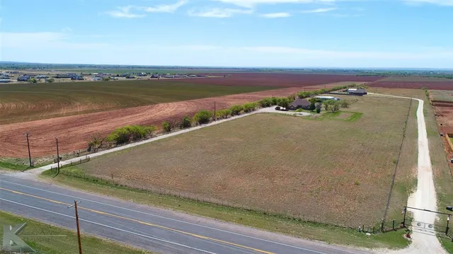 an aerial view of ocean and fields with trees