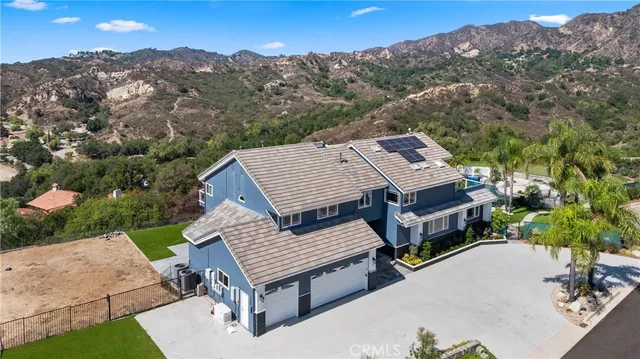 an aerial view of a house with a yard and mountain view in back