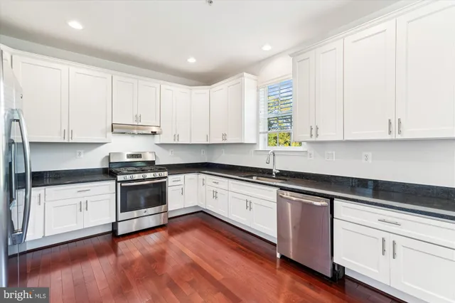 a kitchen with granite countertop white cabinets and stainless steel appliances