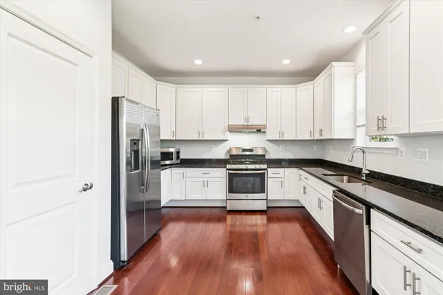 a kitchen with stainless steel appliances a refrigerator and wooden floor