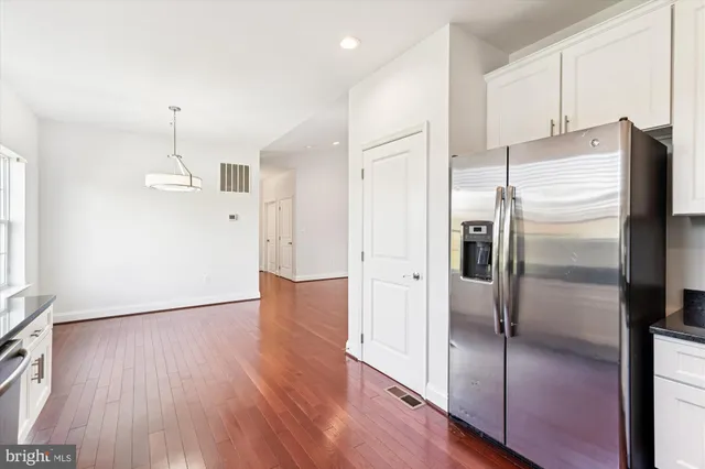 a kitchen with granite countertop wooden floors white cabinets and a window
