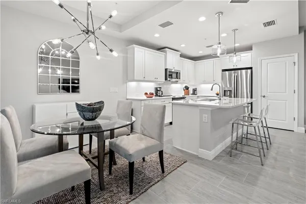 a kitchen with kitchen island a dining table chairs cabinets and stainless steel appliances